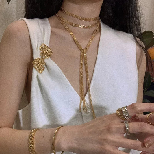 Lange, mehrlagige Halskette mit goldenen, quadratischen Quasten